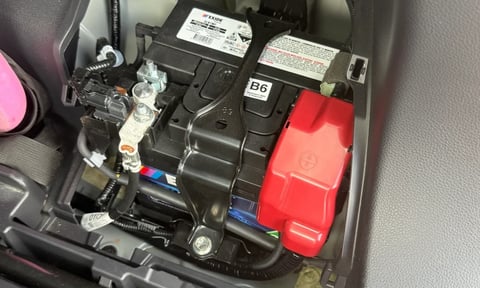 Car engine fuse box with red positive and black negative battery terminals and labeled components